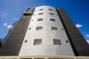 a tall white building with a clock on it at Apartamentos mobiliados em Caruaru in Caruaru