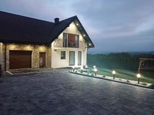 a house with a driveway at night with lights at Noclegi Pod Lasem in Polańczyk