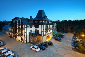 ein großes Haus mit Autos auf einem Parkplatz in der Unterkunft Hotel Royal Baltic 4* Luxury Boutique in Ustka