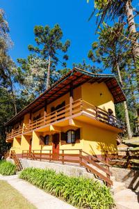 a yellow building with trees in the background at Pousada Sonho Verde in Monte Verde