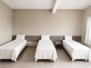 two beds in a room with white walls at HOTEL SB Butia in Butiá