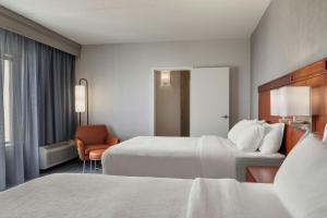 a hotel room with two beds and a chair at Courtyard by Marriott Pittsburgh Airport in Coraopolis +46 photos