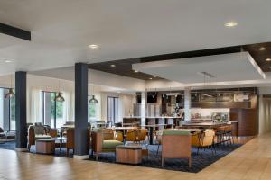 a lobby with a restaurant with tables and chairs at Courtyard by Marriott Pittsburgh Airport in Coraopolis