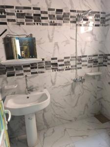 a white bathroom with a sink and a mirror at Safa home in Al Ghuşnah