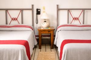 a room with two beds and a table with a lamp at Hotel Posada el Cid in Oaxaca City