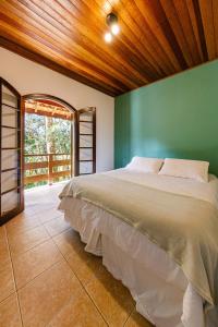 a bedroom with a large bed with a green wall at Pousada Sonho Verde in Monte Verde +113 photos