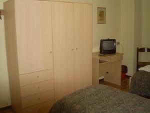ein Schlafzimmer mit einem Bett, einer Kommode und einem TV in der Unterkunft Hotel La Favorita in Casalmaggiore