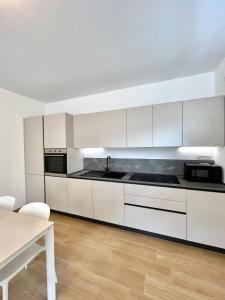 a kitchen with white cabinets and a table at Panoramic and view apartments in Lezzeno