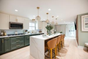 a kitchen with green cabinets and a bar with chairs at Coastal Sands Inn in Wildwood