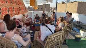 a group of people sitting in chairs under an umbrella at Grand Backpackers Hostel Luxor in Luxor