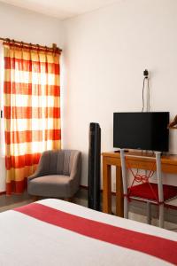 a bedroom with a bed and a tv and a chair at Hotel Posada el Cid in Oaxaca City