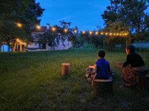 two people sitting on tree stumps in a field at night at Вила Хармония Harmony Cottage in Kyustendil