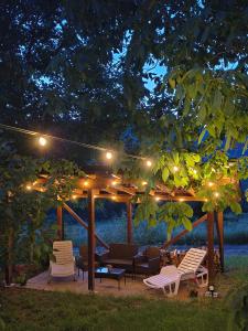 a gazebo with lights and chairs under a tree at Вила Хармония Harmony Cottage in Kyustendil