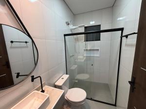 a bathroom with a shower and a toilet and a sink at Casa completa com wifi, garagem, próximo ao centro in Piatã