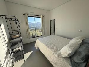 a white bedroom with a bed and a window at Casa completa com wifi, garagem, próximo ao centro in Piatã