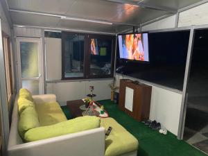 a living room with a couch and a flat screen tv at Къща за гости Зеленец in Sozopol