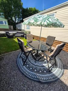 a patio table with two chairs and an umbrella at Escape in Carnforth Lodge - Sleeps 6 in Carnforth
