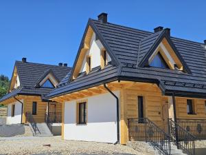 a house with a black roof at Tatrzańska Osada 2 - Domki przy stoku narciarskim w Białce Tatrzańskiej in Białka Tatrzańska