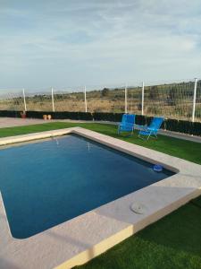 a swimming pool with two blue chairs next to it at Cueva mágica de Raspay in Raspay +17 photos