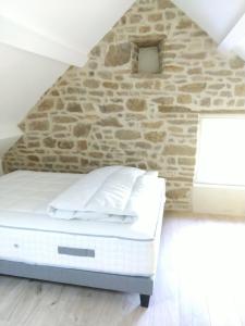 a bed in a room with a stone wall at L' Eminence in Clécy