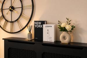 a black table with a clock and books and a vase with flowers at Newcastle City Centre 2BR, Near Central Train Station in Newcastle upon Tyne