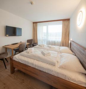 a bedroom with a large bed and a desk at Lipno - apartmán C404 in Frymburk