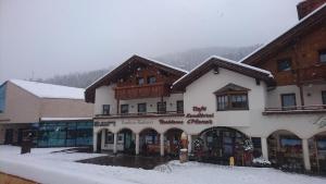 Un edificio con nieve en el suelo frente a él. en Residence Ploner, en San Cassiano