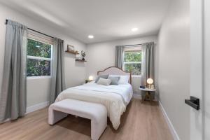 a white bedroom with a large bed and two windows at Charming house in Midtown District in Reno