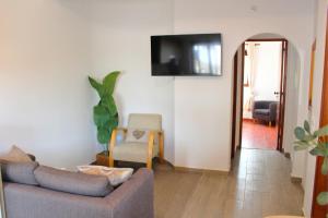 a living room with a couch and a tv on the wall at Casa do Castelo - Calm & lovely 2-bedroom Apt Near the Beach in Sesimbra