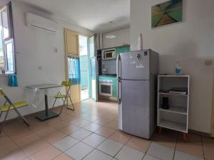 a kitchen with a stainless steel refrigerator and a table at SCI Severin in Pointe-à-Pitre