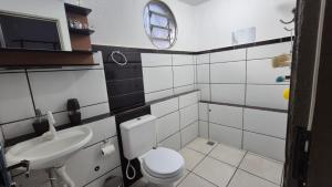 a bathroom with a white toilet and a sink at Casa Pitanga Quarto in Barra do Garças