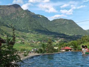 a group of people sitting in a swimming pool with mountains in the background at De Mont Retreat Sapa in Sapa