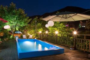 a blue swimming pool with an umbrella and a patio at Milyang Sweety Pension in Miryang