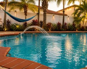 a swimming pool with a fountain in front of a house at The Oasis, Miami Lakes in Miami Lakes