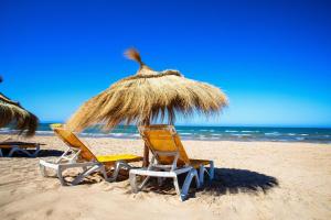 two chairs and a straw umbrella on the beach at The Village Resort By Acquaviva Gammarth in Gammarth +3 photos