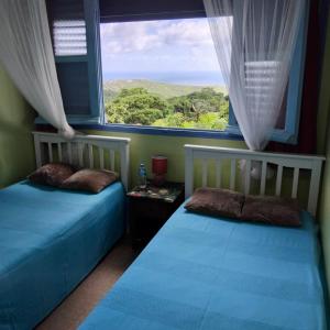 two beds in a room with a large window at Cheerful 3 bedroom home with stunning views in Quartier la Fleury Guiné