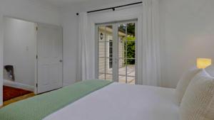 a bedroom with a white bed and a sliding glass door at Wood Street Haven in Greytown