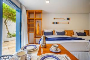 a bedroom with two beds and a table with plates on it at Vila Maria Pousada in Jericoacoara