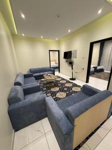 a living room with blue couches and a tv at شقق ضيافة خاصة in Abha