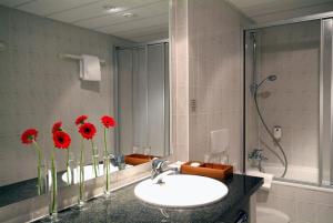 ein Badezimmer mit Waschbecken und roten Blumen in einem Spiegel in der Unterkunft Quick Hotel Dresden 24H Self Check-in in Dresden + 18 Fotos