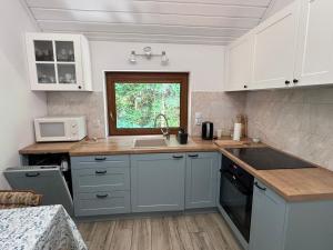 a kitchen with white cabinets and a sink and a window at Jaromierz Dom nad jeziorem in Jaromierz