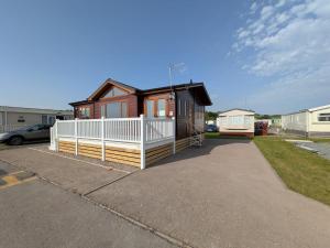 a small house with a white fence in a parking lot at Sea View Retreat Lodge in Heysham