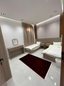 a bedroom with two beds and a red rug at سويتات توت in Al Mikhlaf
