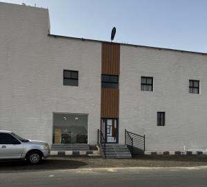 a white building with a car parked in front of it at سويتات توت in Al Mikhlaf