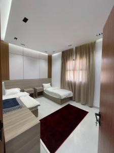 a bedroom with two beds and a mirror at سويتات توت in Al Mikhlaf