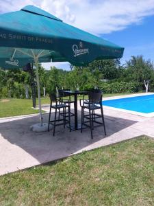 a table and chairs under an umbrella next to a pool at Villa Valinor in Slatina Varoš