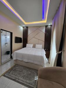 a bedroom with a large white bed and a tv at O2 Continental Suites in Kubwa