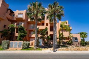 a building with palm trees in front of a street at Calma Suite Apartment - Mar Menor Golf Resort in Torre-Pacheco