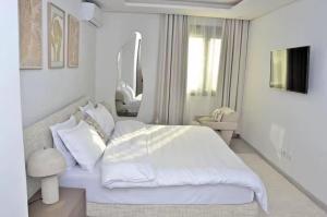 a white bedroom with a large bed and a mirror at F3 ngor virage in Dakar