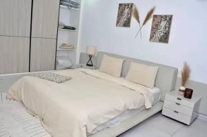 a white bedroom with a large bed with white sheets and pillows at F3 ngor virage in Dakar +6 photos